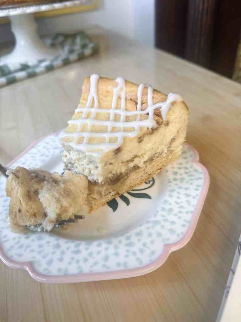 Close-up of a slice of Cinnamon Roll Cheesecake on a white plate.