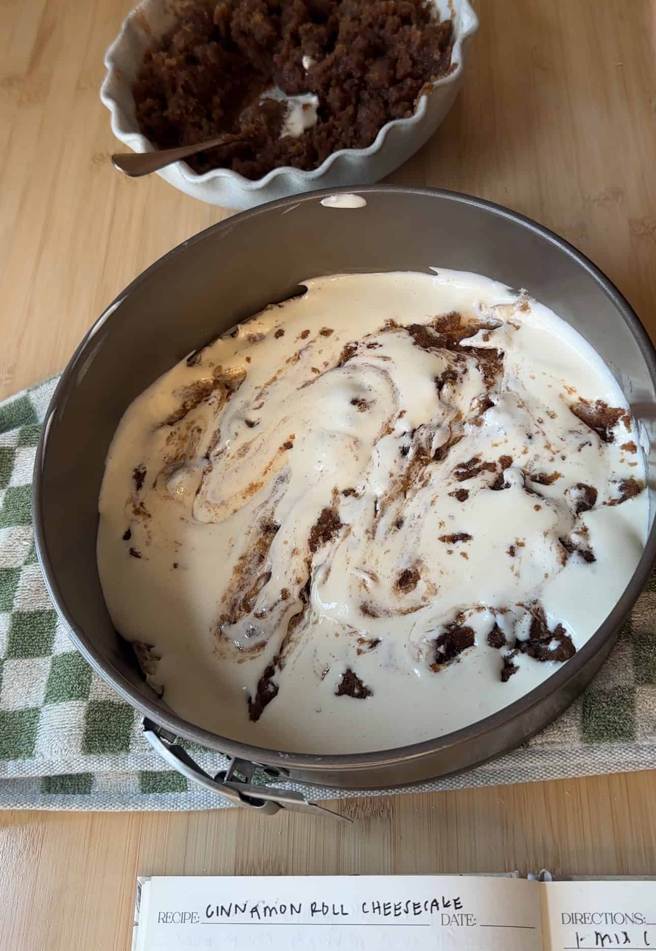 Cinnamon sugar mixture being swirled into the cheesecake batter.