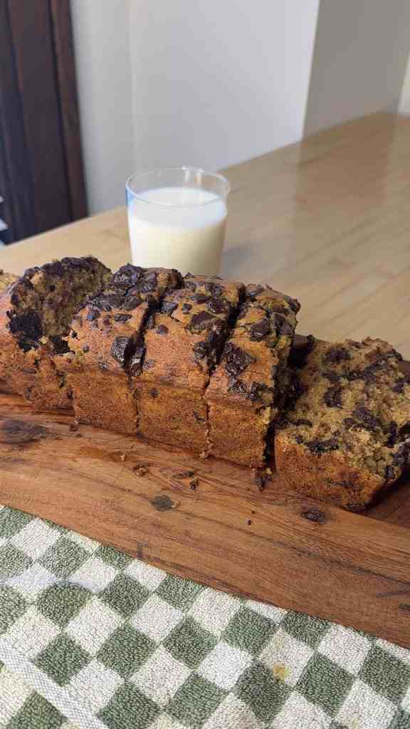 my dark chocolate espresso banana bread sliced up on a cutting board with a glass of milk ready to be enjoyed.