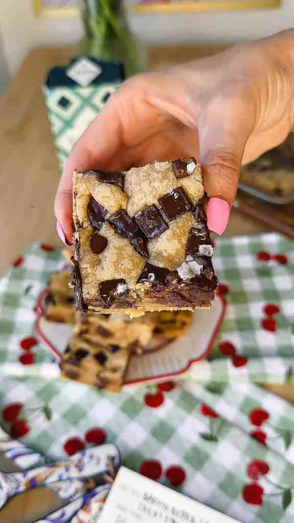 a close up shot of ym brown butter sheet pan chocolate chunnk cookie s- shows the gooey chocolate chunks with the flakey sea salt