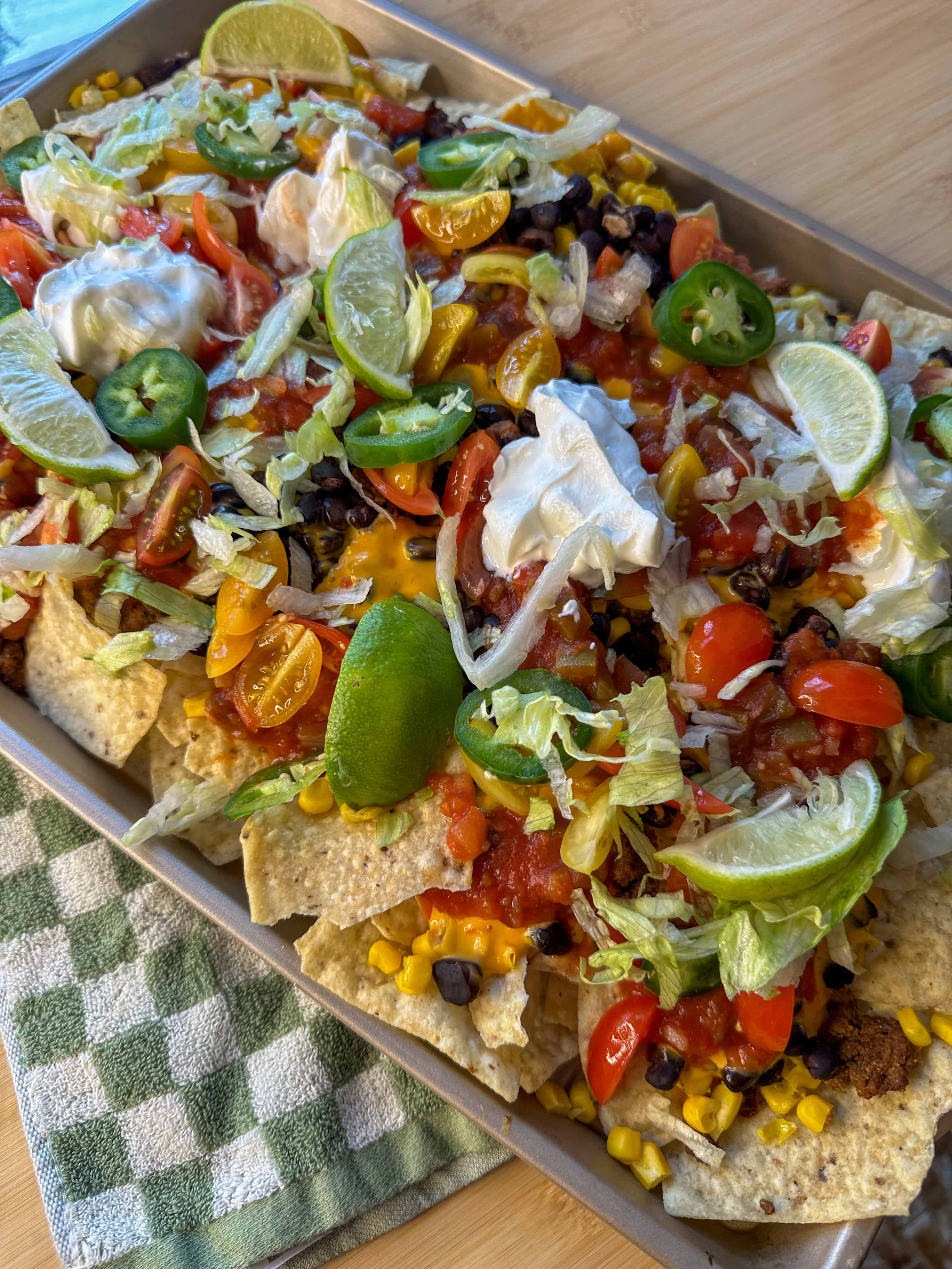 a final image of my sheet pan nachos fresh oit of the oven with all of the cold toppings, ready to be enjoyed by my family!
