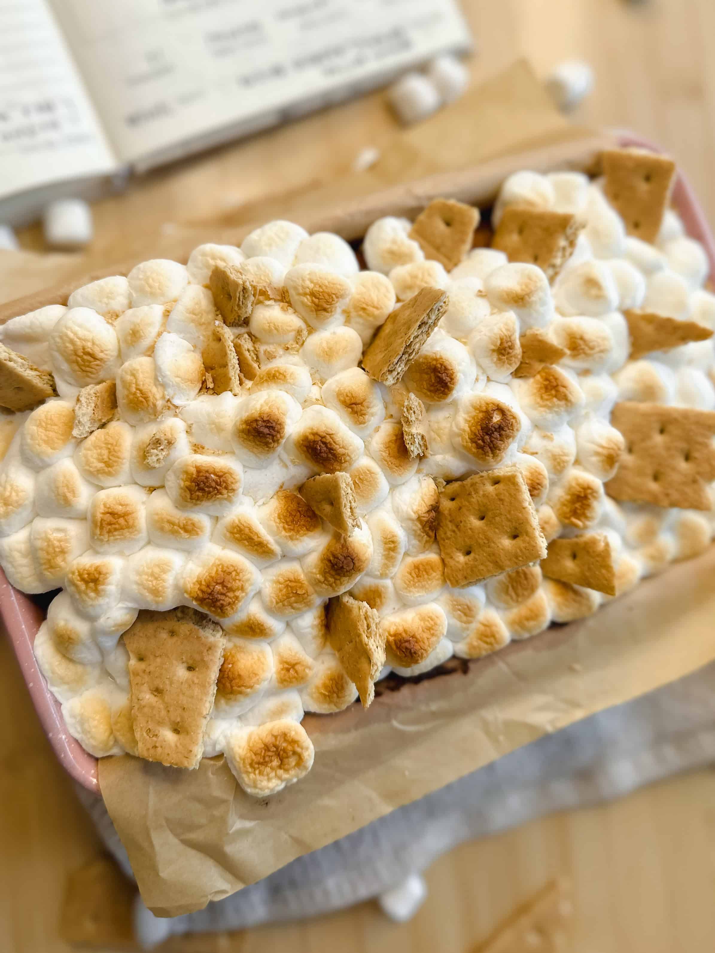 lose-up of a slice of brown butter s’mores banana bread with melted chocolate and marshmallows.